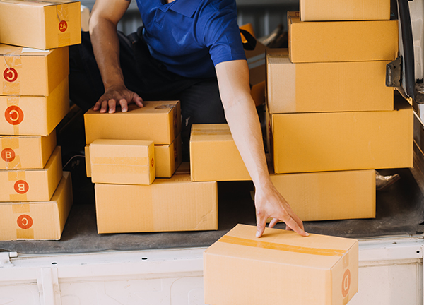 Empleado de paqueteria revisando y reuniendo varios paquetes en una van